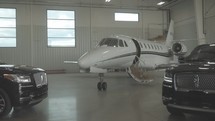 Private jet and SUVs in a hanger