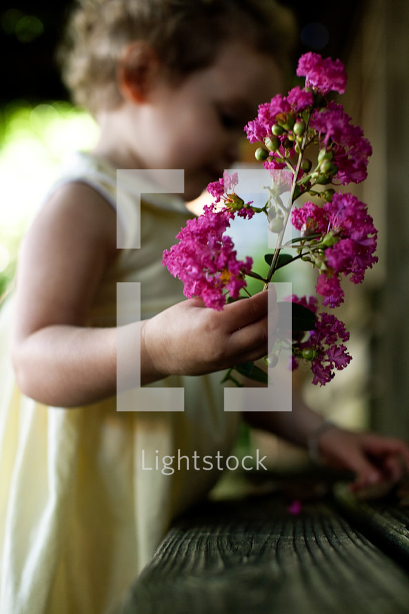 toddler girl holding branch of flowers