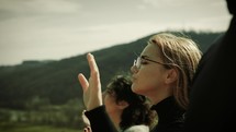 woman with hands raised in praise on a mountaintop 