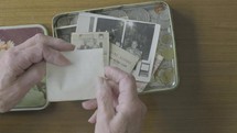 elderly caucasian man looking at old photographs and love notes in n old memory box