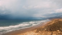 Fast motion waves in Atlantic ocean coast in Morocco with dark clouds coming before storm Travel background

