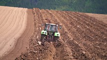 Tractor plowing field, deep plow tillage cultivate soil in spring agriculture farming
