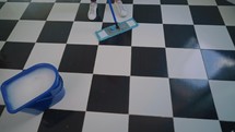 Close up of mop cleaning a black and white floor.
