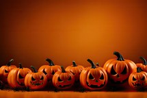 Halloween pumpkins with scary faces on orange background with copy space