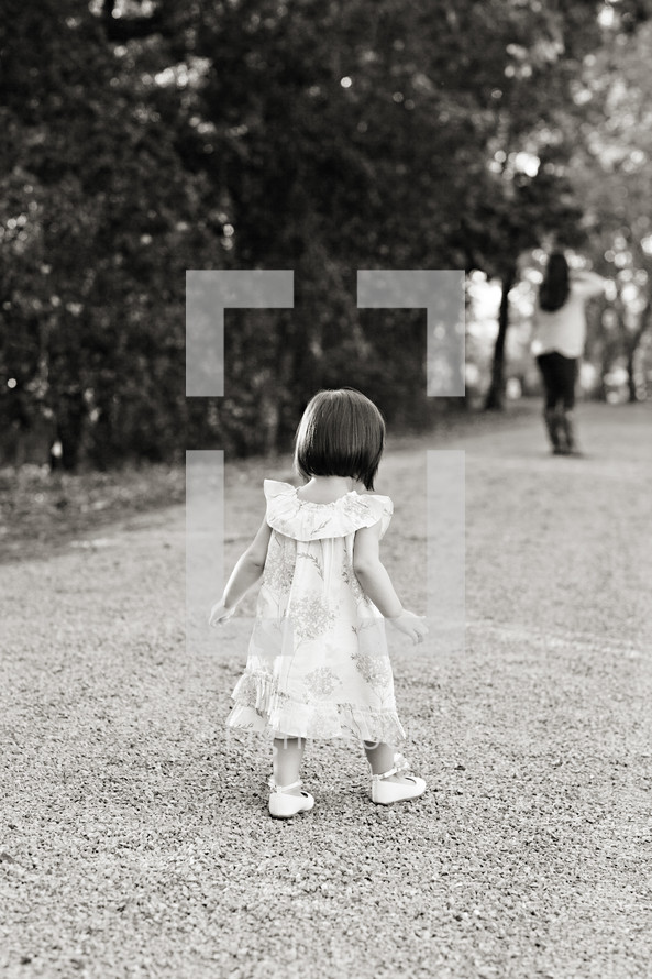 toddler girl walking in dress down gravel road