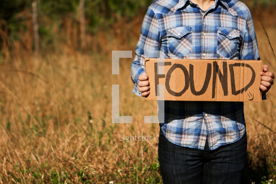 Man holding "Found" cardboard sign
