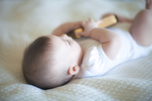 Baby on a bed holding a Bible.