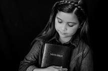 A young girl holding a Bible close to her heart 