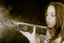 a woman blowing off dust from a Bible 