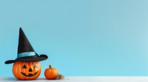 Halloween pumpkins with witch hat on blue background, copy space