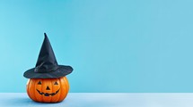 Halloween pumpkin with witch hat on blue background. Space for text