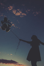 A silhouette of a woman holding balloons 