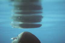 a girl swimming under water rising to the surface 