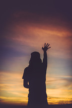 silhouette of a woman with hand raised 