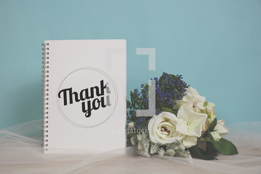 word thank you on a notebook and flower bouquet 