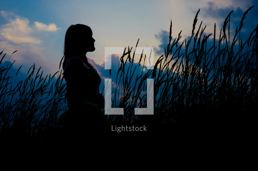 silhouette of a woman standing in a field 