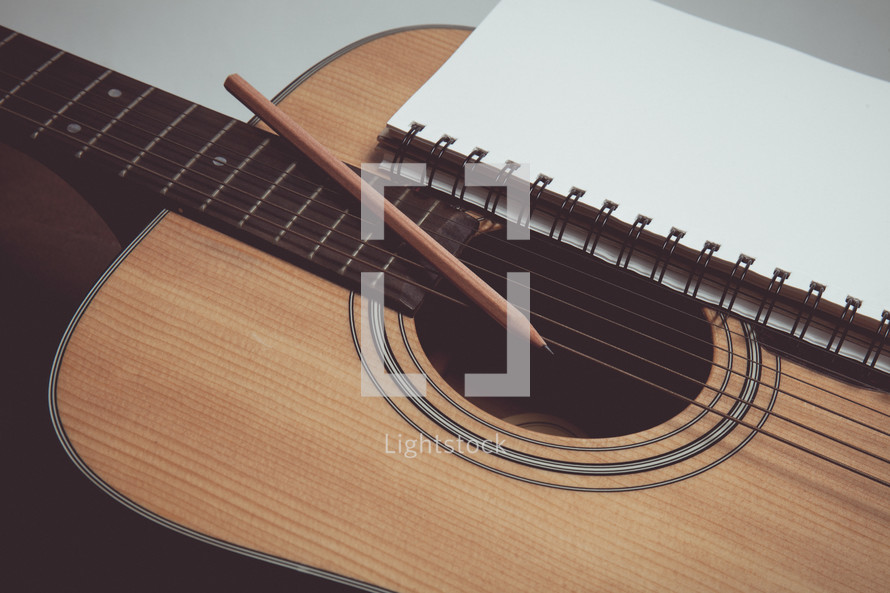 pencil and journal on a guitar 