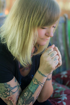 Tattooed woman praying.