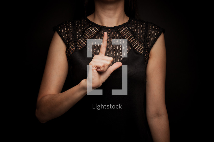 a woman holding an L over her chest 