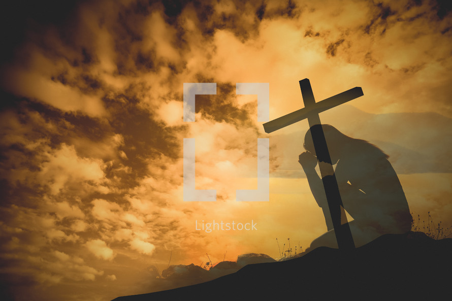 silhouette kneeling in prayer in front of a cross