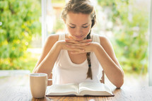 a woman reading a Bible and praying in the morning 