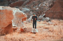 man standing beside of red rocks 