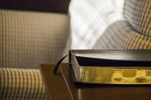 Bible on an end table next to an arm chair 