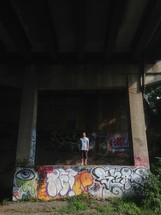 man standing on a graffiti covered wall 