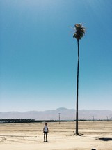 woman standing next to a tall palm tree 