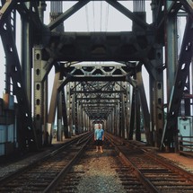 man standing between two sets of railroad tracks 