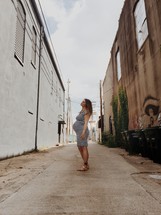 pregnant woman standing in an alley 