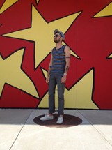 man standing in front of an abstract painted wall with stars