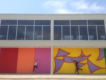 man and woman dancing and jumping in front of abstract painted walls