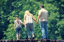 family holding hands walking in a creek bed