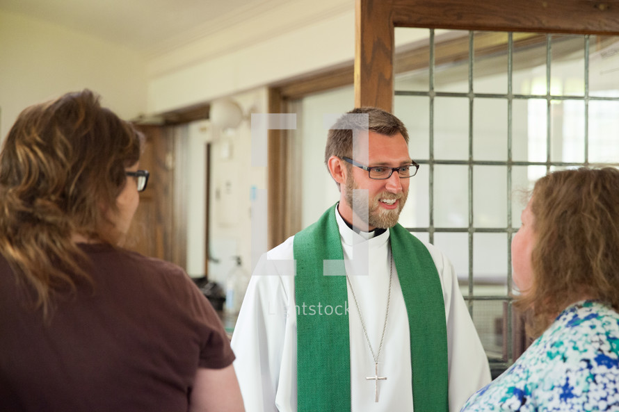 a priest greeting women in church 