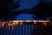 string of lights on a railing with snow 