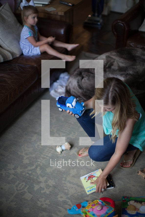 a mother picking up toys off the floor 