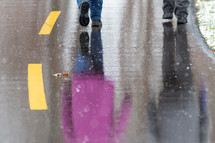reflection of people walking on wet asphalt 