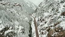 Aerial view over a highway in the snowy Rocky Mountains.