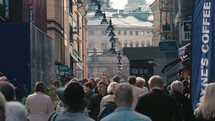 crowds walking down a narrow street in a European town 