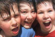 a group of 3 very happy young friends after a water fight