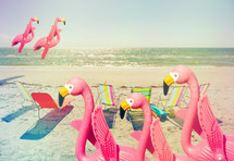 pink plastic flamingos and lounge chairs on a beach, humorous composite