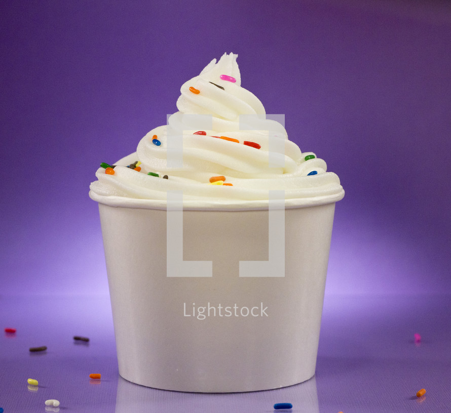 Cup of Vanilla Frozen Yogurt with Sprinkles Against a Purple Background