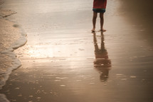 Wading child reflected in the water.