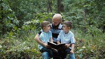 a father reading to his sons in the woods 