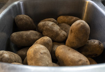 A sink full of potatoes waiting to be peeled