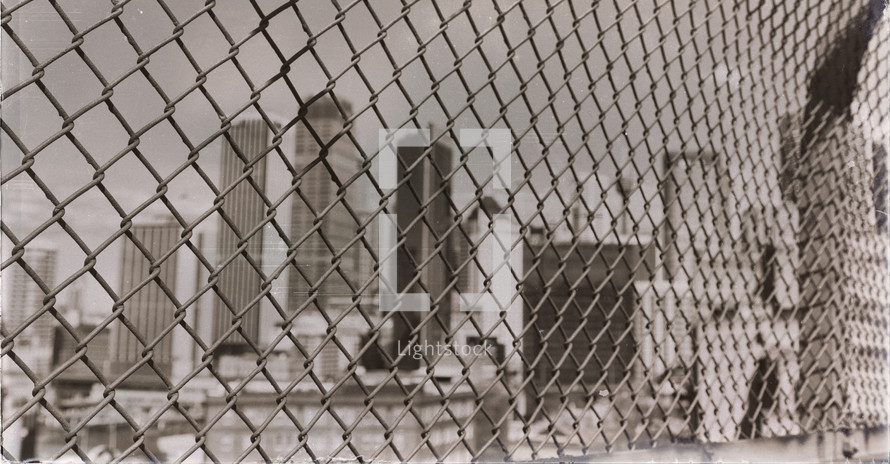 view of a city through a chain link fence 