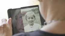 woman caucasian looking at old photographs on a tablet 