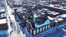 Circling an abandoned church with holes and broken boards as a roof in a small neighborhood in St. Louis, Missouri with snow during winter time.