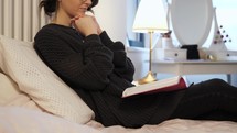a woman reading a Bible and praying in bed 
